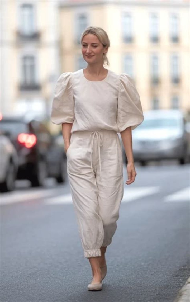 Woman in white puff sleeve blouse with tailored straight leg trousers and minimalist jewelry